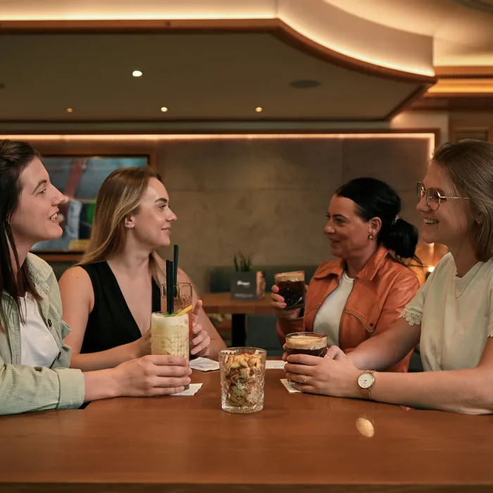 Vier Frauen genießen Getränke und unterhalten sich an einem modernen Cafétisch